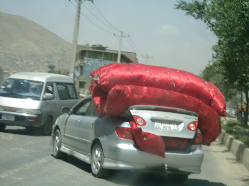 Cots and pillows spilling out of a car in Kabul