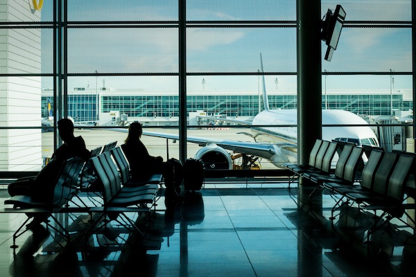 travelers at an airport gate area looking over a plane