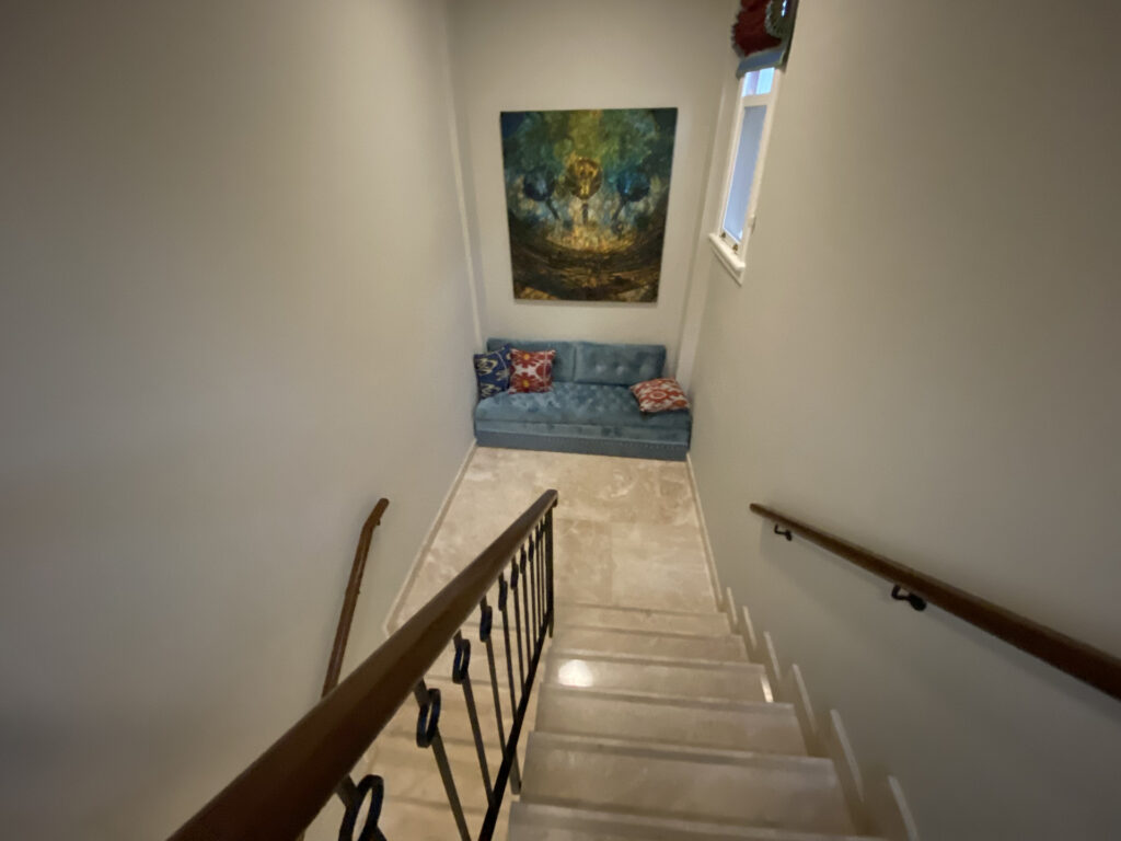 Staircase landing with a blue couch and green painting