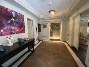 Townhouse entrance with herringbone floors and vibrant art leading to a staircase