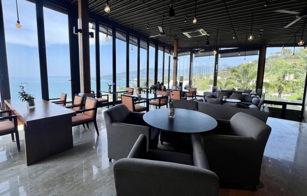 A room with tables and chairs and a view of the ocean