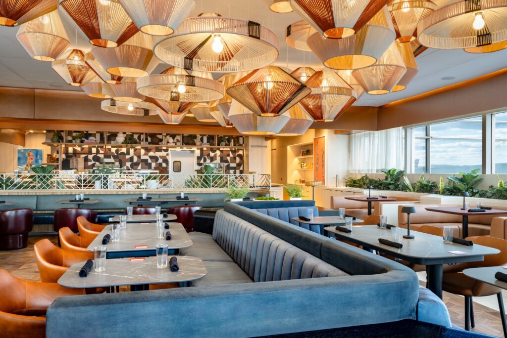 Diner-style seating area at the new Capital One Lounge DCA. Bar area in the background, with lantern-style lighting hanging from the ceiling